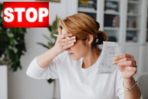 donna con bolletta in mano ed occhi chiusi con scritta stop in rosso