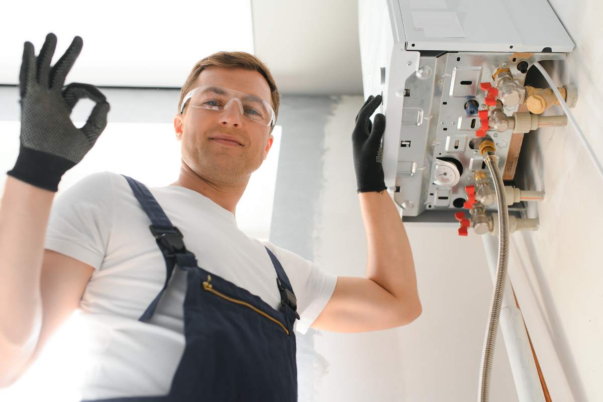 tecnico che lavora sulla caldaia e fa segno ok