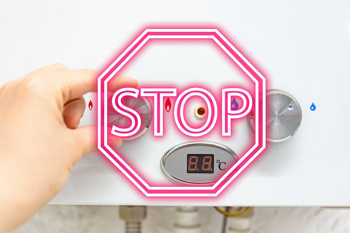 mano su una caldaia e scritta stop in rosso