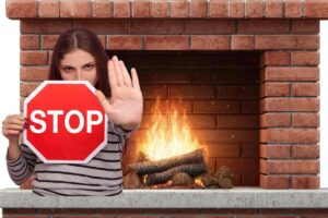 caminetto acceso con fiamma e donna coma mano e segnale di stop