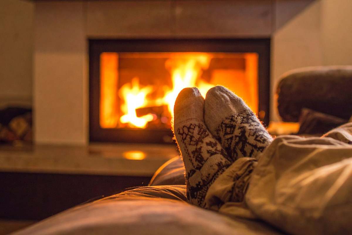 caminetto acceso con fiamme e piade allungati vicino