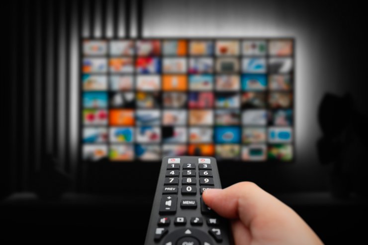 Una TV sullo sfondo ed un telecomando in primo piano