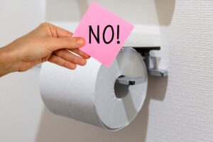 rotolo di carta igienica e mano con foglietto e scritta no