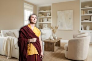 ampio salotto moderno come sfondo e in primo piano un monaco buddista