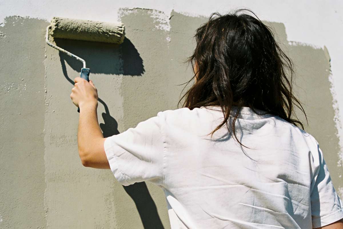 persona che dipinge parete di verde con il rullo 