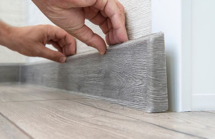 uomo che monta battiscopa sul muro