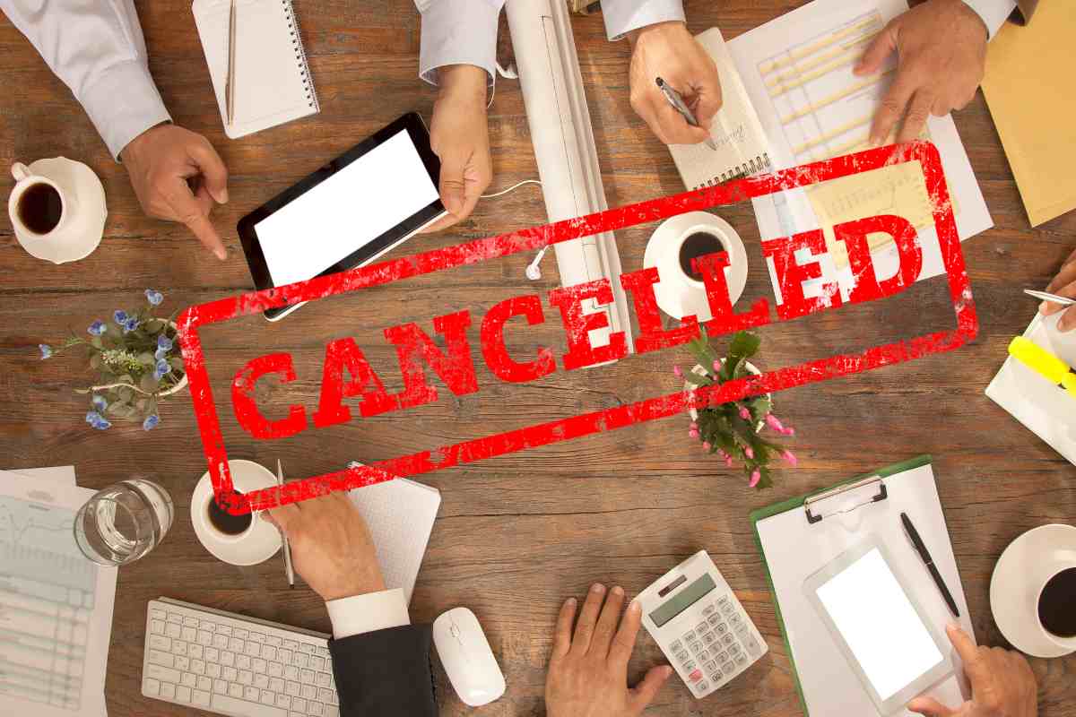 persona con mani sul tavolo e scritta cancellato in rosso