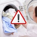 donna carica lavatrice e segnale di pericolo in evidenza