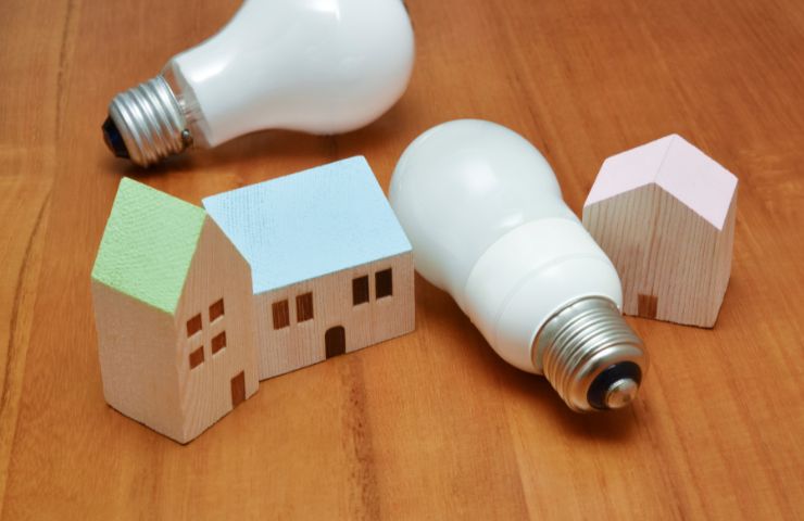 sagoma di case e lampadine su superficie in legno 