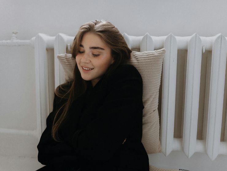 donna con cuscino vicino al termosifone 