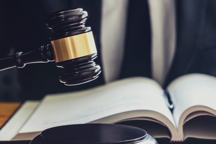 Un giudice con davanti un libro di legge che sbatte il proprio martello da giudice