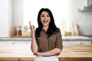 donna con dito alzato e sfondo di una cucina