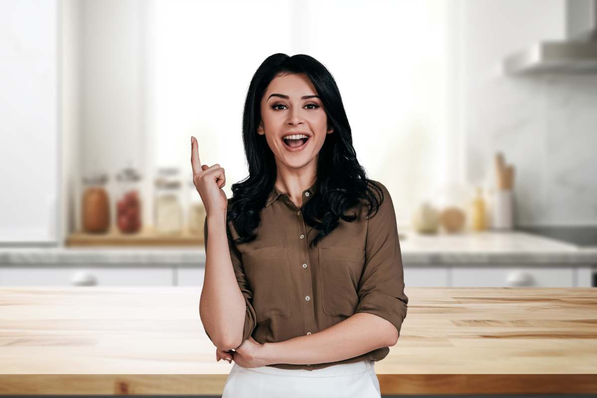 donna con dito alzato e sfondo di una cucina