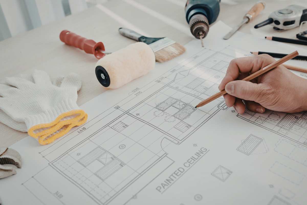 mano ch disegna progetto su cartina e altri oggetti da disegno