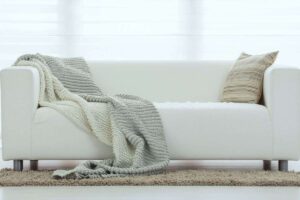 divano bianco con cuscini e plaid