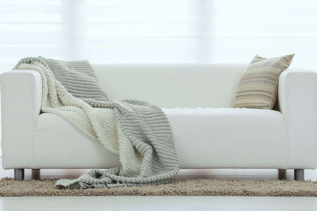 divano bianco con cuscini e plaid