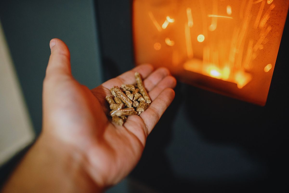 stufa a pellet accesa e mano con del pellet in evidenza