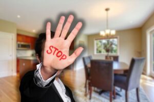 cucina con lampadario sullo sfondo e mano di uomo con scritta stop