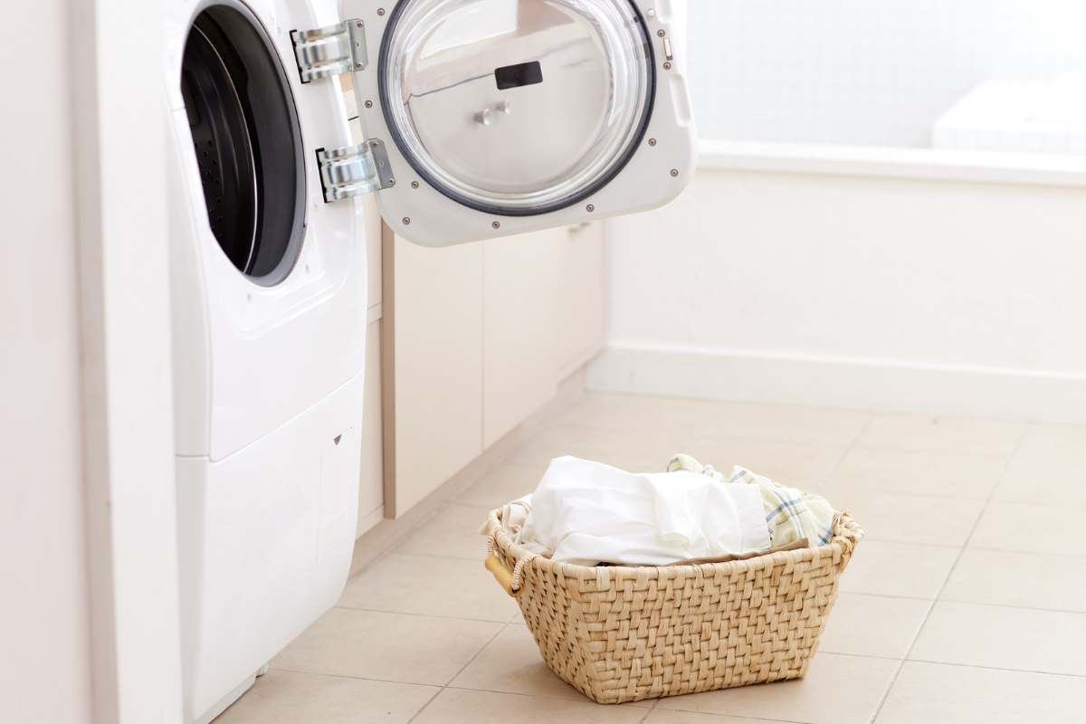 lavatrice aperta e cesto con i panni accanto 