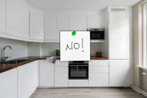 spaziosa cucina tutta di colore bianco e un post it su cui c'è scritto no
