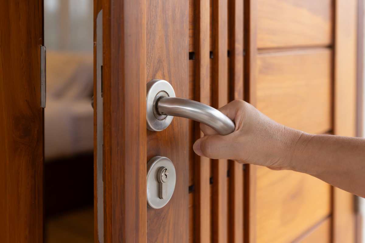 mano su maniglia di una porta che si apre