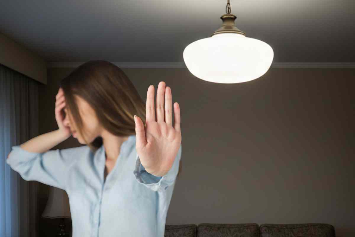 ragazza che fa il segno dello stop e una plafoniera nello sfondo