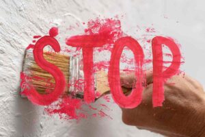 scritta stop in rosso e mano che pittura muro