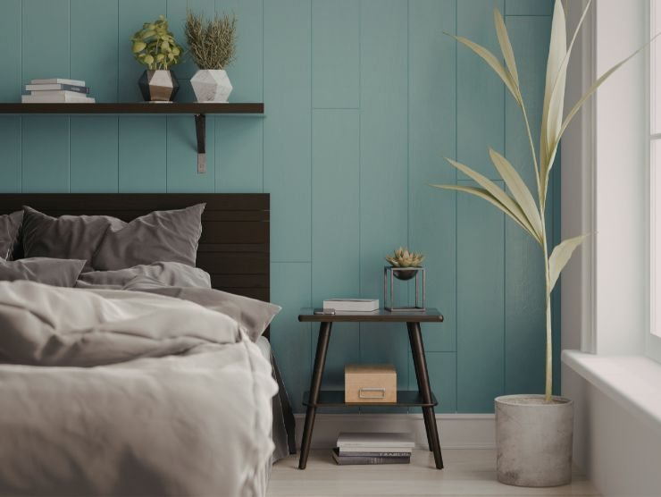 camera da letto con parete in doghe verde salvia, tavolino con lampada e pianta in vaso