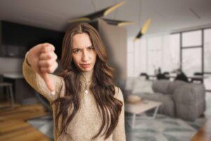 cucina e soggiorno in open space sullo sfondo e donna triste con pollice in giù