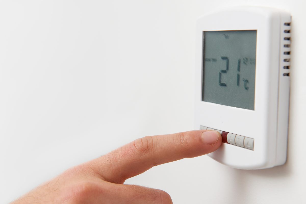 mano che tocca termostato impostato a 21 gradi