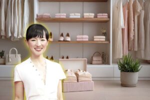 Marie Kondo in primo piano sorridente e sfondo di una cabina armadio ben in ordine