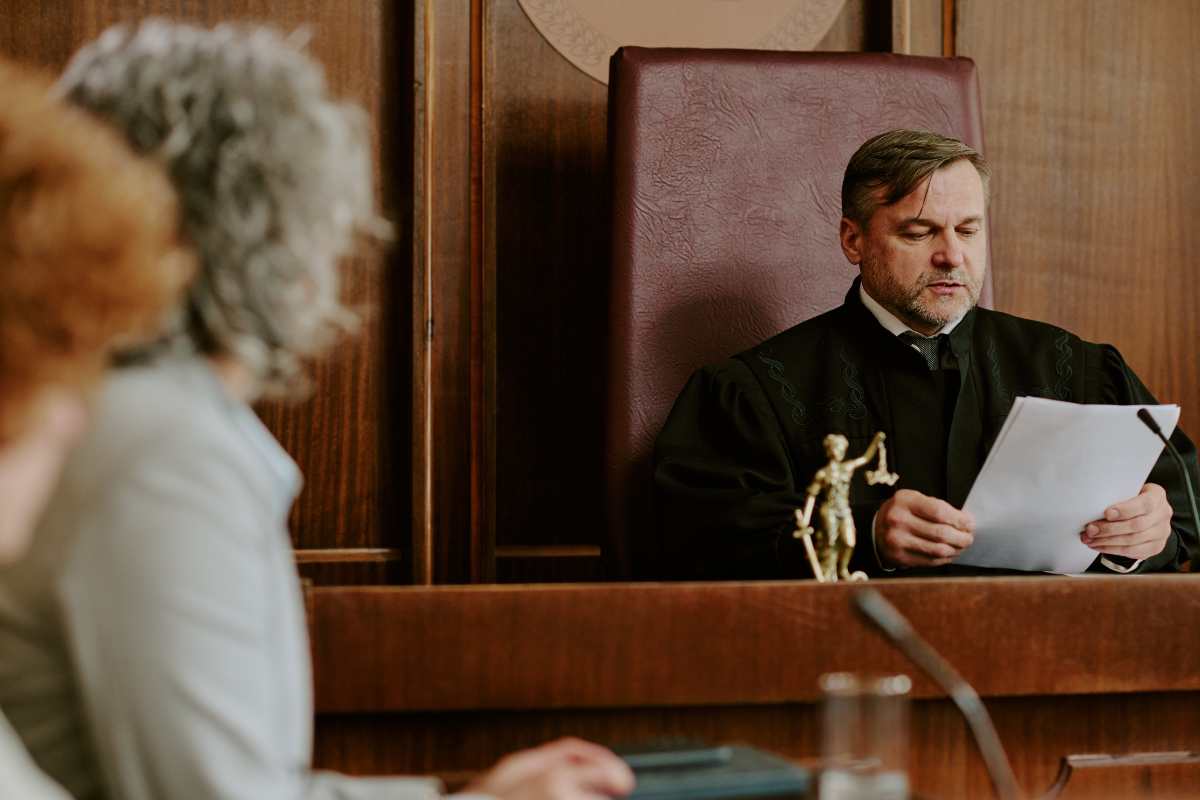 giudice che legge sentenza con persone davanti 