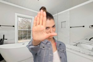 donna con mano che fa segno di stop e bagno nello sfondo