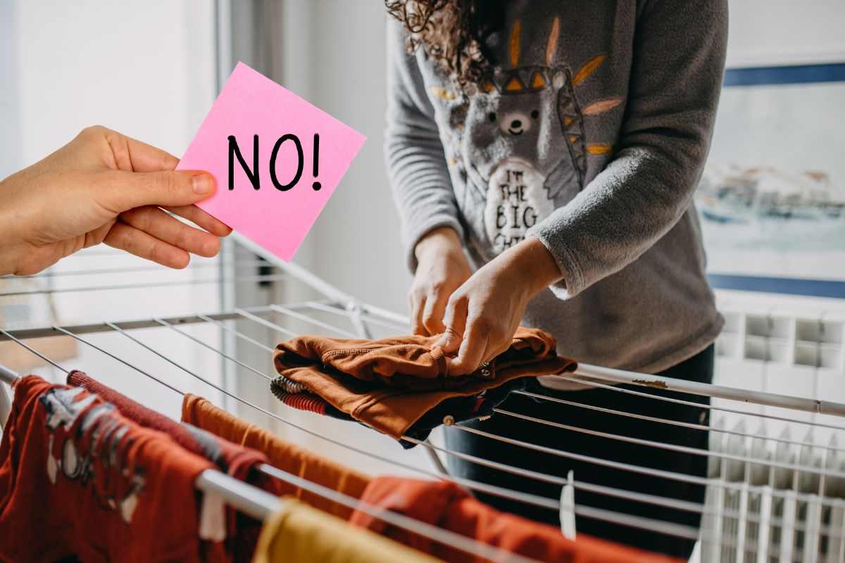donna che stende panni in casa e mano con foglietto rosa e scritta no