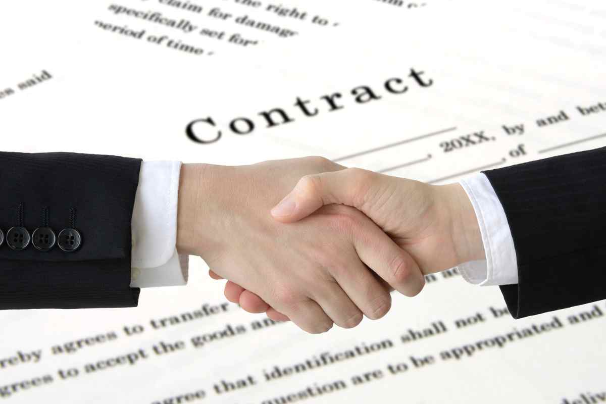 mani che si stringono e sfondo di fogli 