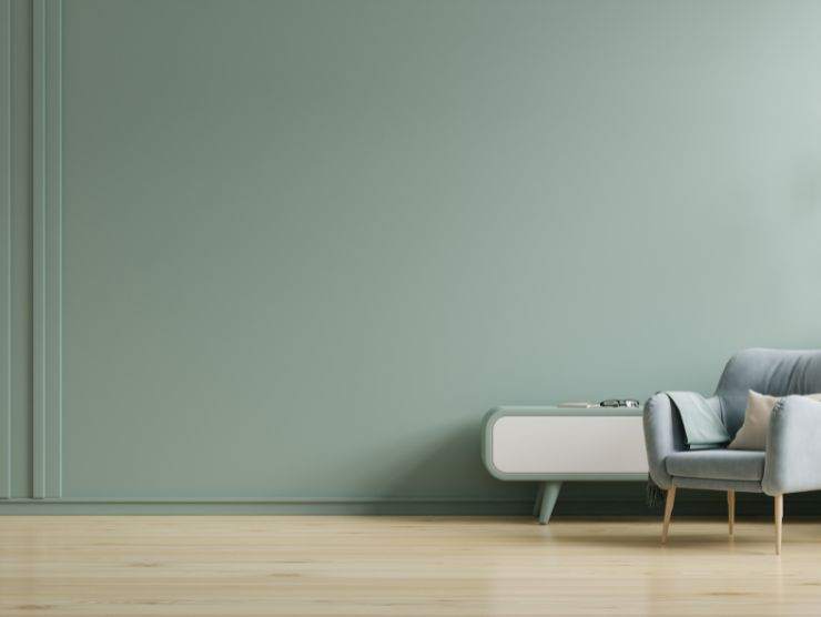 parete color verde salvia e piccola poltrona con tavolino