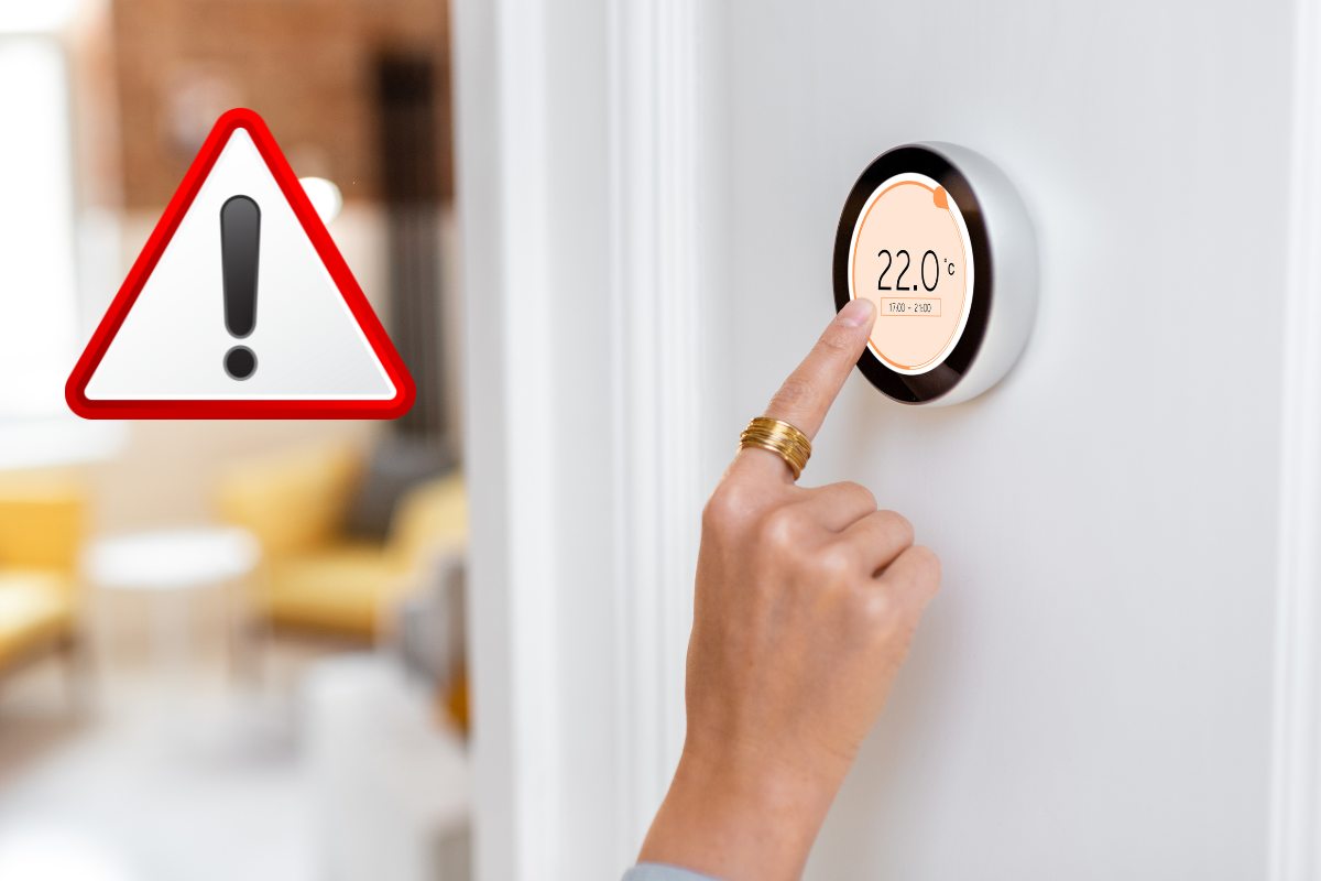 mano su termostato e simbolo di attenzione