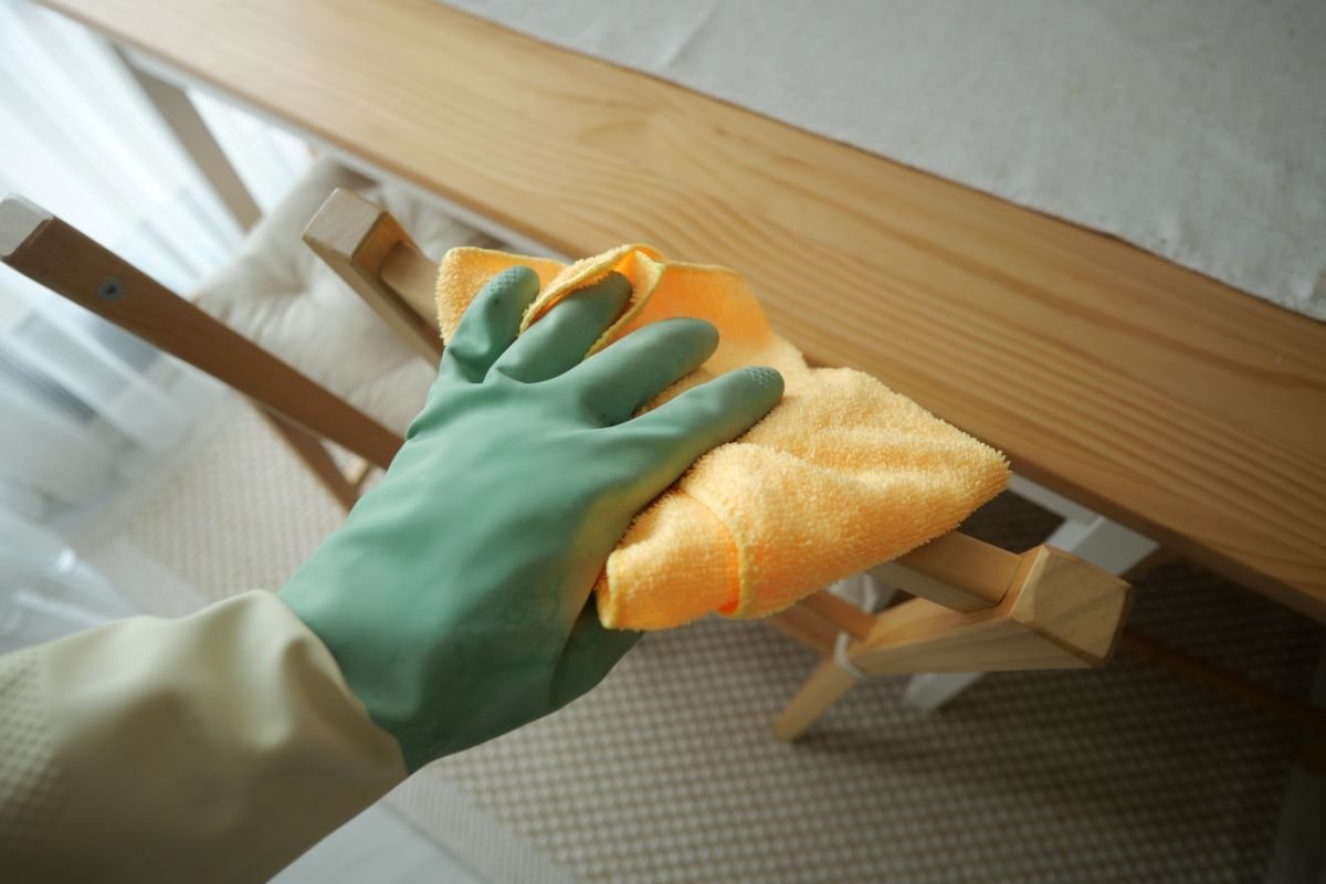 mano che impugna un panno per pulire un mobile in legno