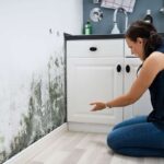 donna in cucina che indica una grande macchia di umidità sulla parete