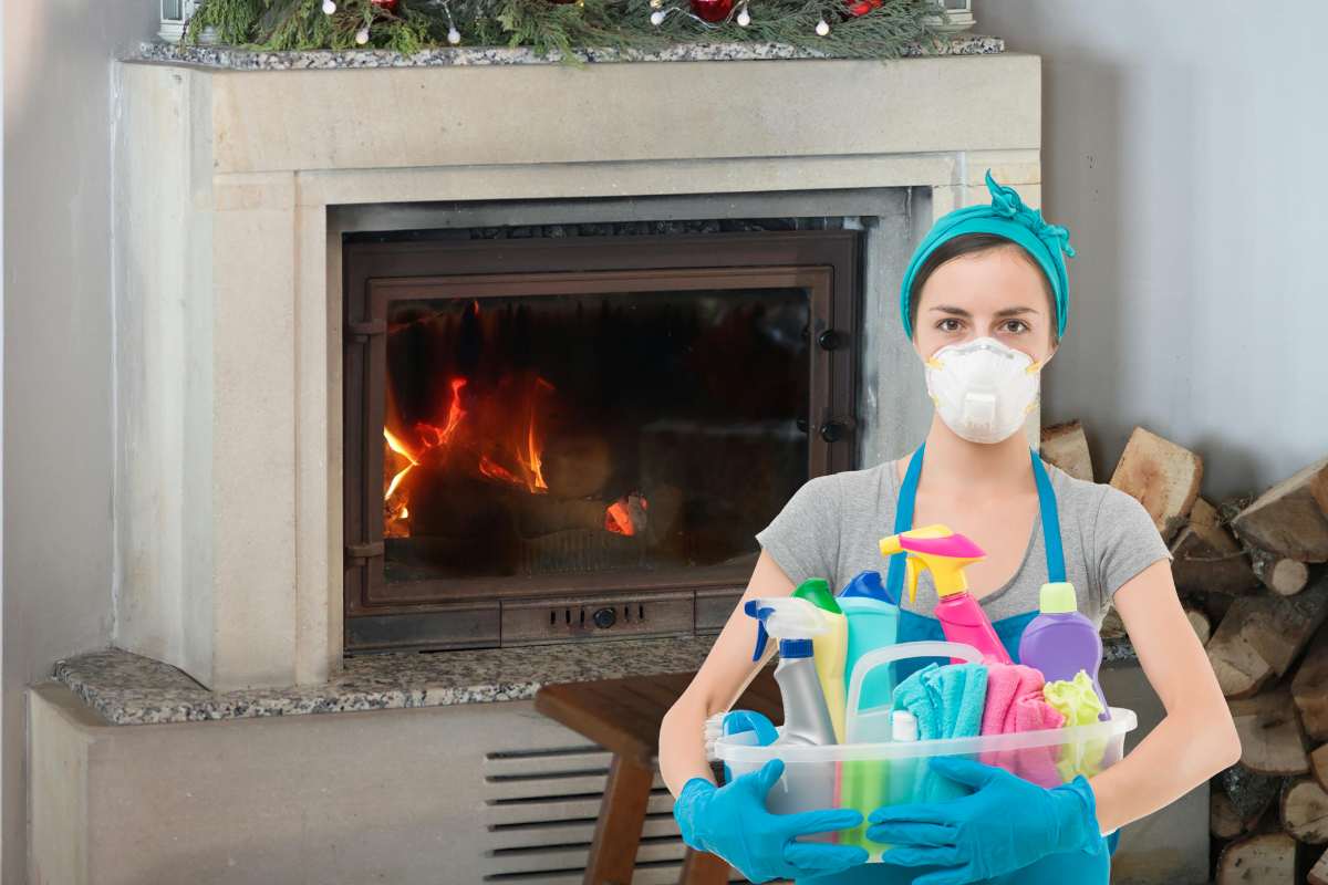 Un termo camino con il vetro annerito ed una donna con prodotti per le pulizie