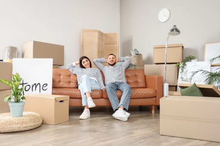 Una giovane coppia sul divano di casa con dei scatoloni nel salone