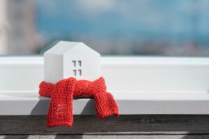 Una miniatura di una casa avvolta da una piccola sciarpa, su una mensola avvolta