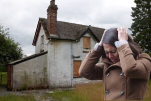 Una casa occupata ed una donna disperata in primo piano