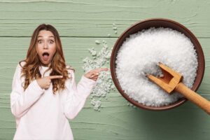 Una donna che indica una ciotola di legno contenente il sale