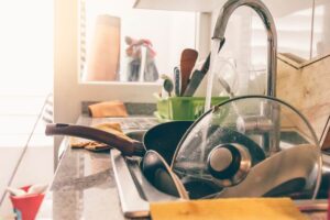 Una cucina caotica con tanti piatti dentro il lavandino