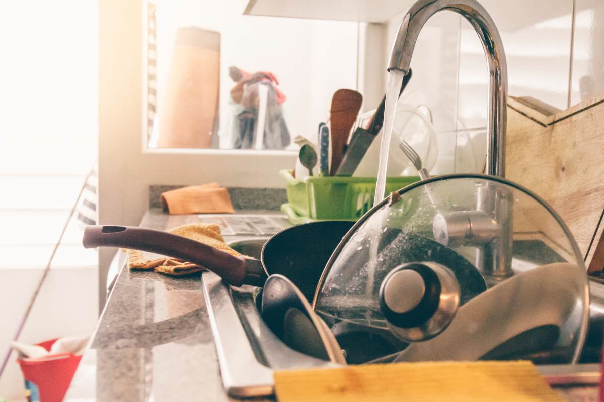 Una cucina caotica con tanti piatti dentro il lavandino