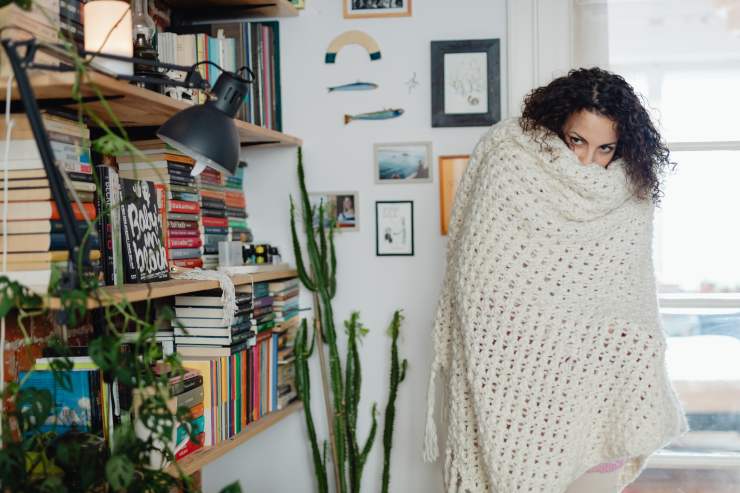 Una ragazza che si copre con una coperta in casa