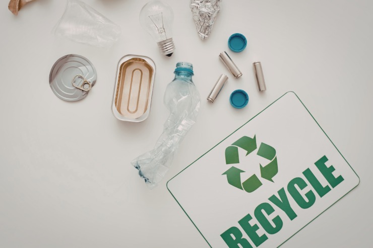 Diversi elementi riciclabili con sotto il simbolo del riciclaggio