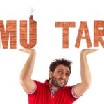 Un uomo che sorregge due scritte fatte in muratura "IMU" e "TARI"