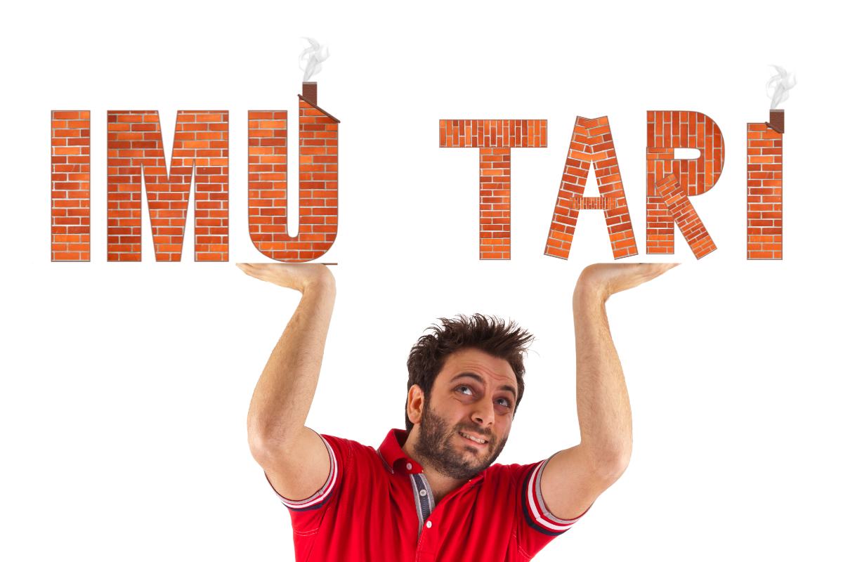 Un uomo che sorregge due scritte fatte in muratura "IMU" e "TARI"